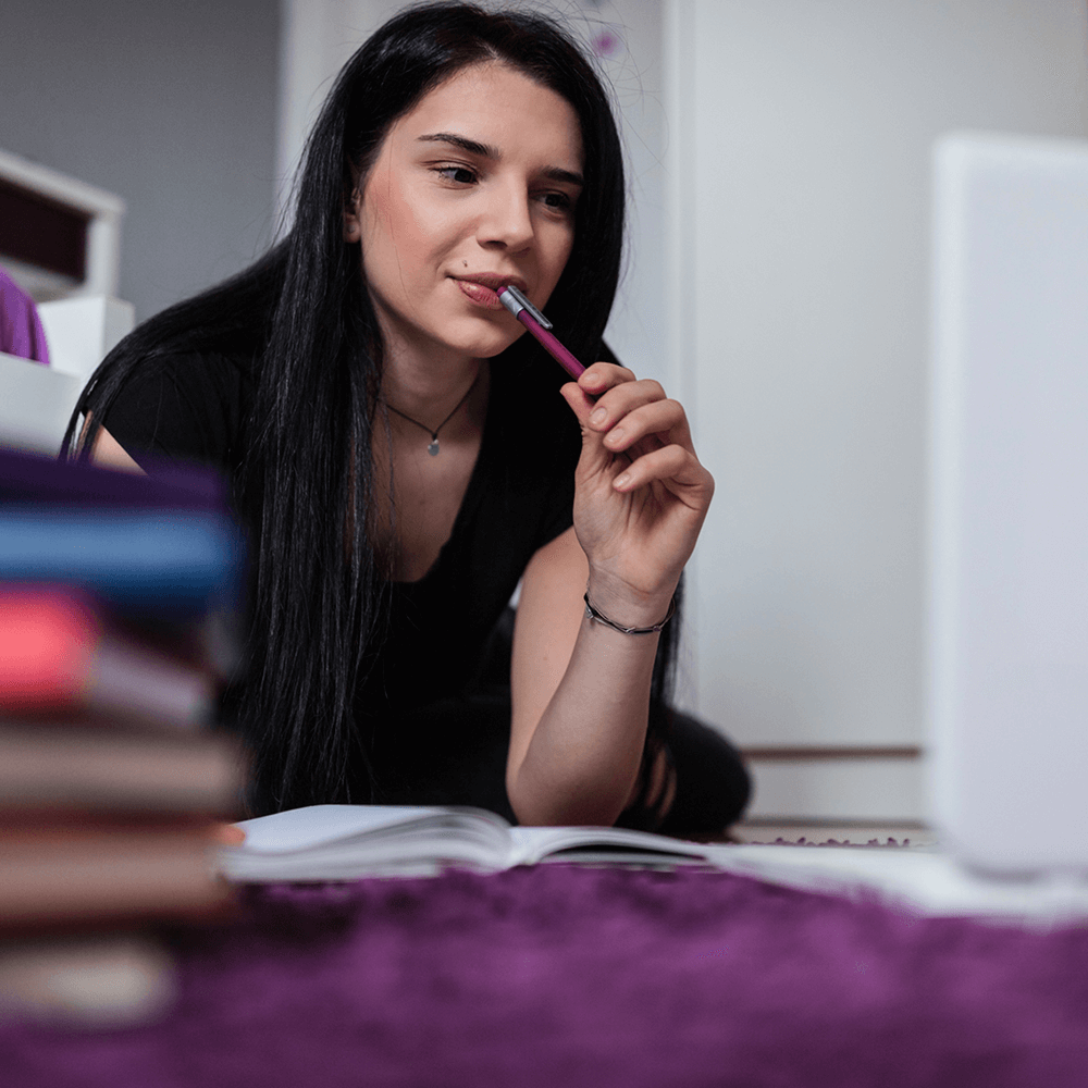 student in front of the window holding a text book